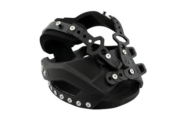 Produktfoto eines schwarzen Goodsmith-Hufschuhs an einem Hufmodell. Die Perspektive zeigt den Schuh leicht von vorne rechts, mit klarem Fokus auf den seitlichen Kunststoff-Schalenbereich, die Schraubenköpfe der Verschlüsse und die markanten Nietendetails am unteren Rand. Das schwarze Polster ist ebenfalls sichtbar.