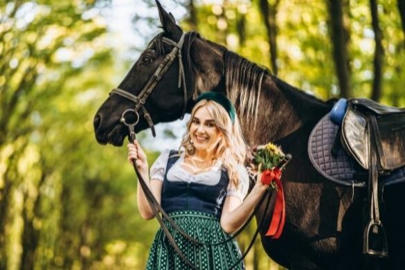 Fotoshooting Pferd Ideen: Frau im Dirndl steht vor einem Pferd.