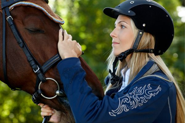 Gelassenheitstraining Pferd: Reiterin streichelt Pferdekopf