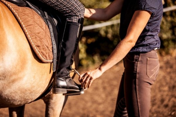 Schenkelhilfen: Reitlehrer zeigt eine Schenkelhilfe.