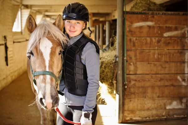 Schulpferd mit Reitschülerin in der Stallgasse