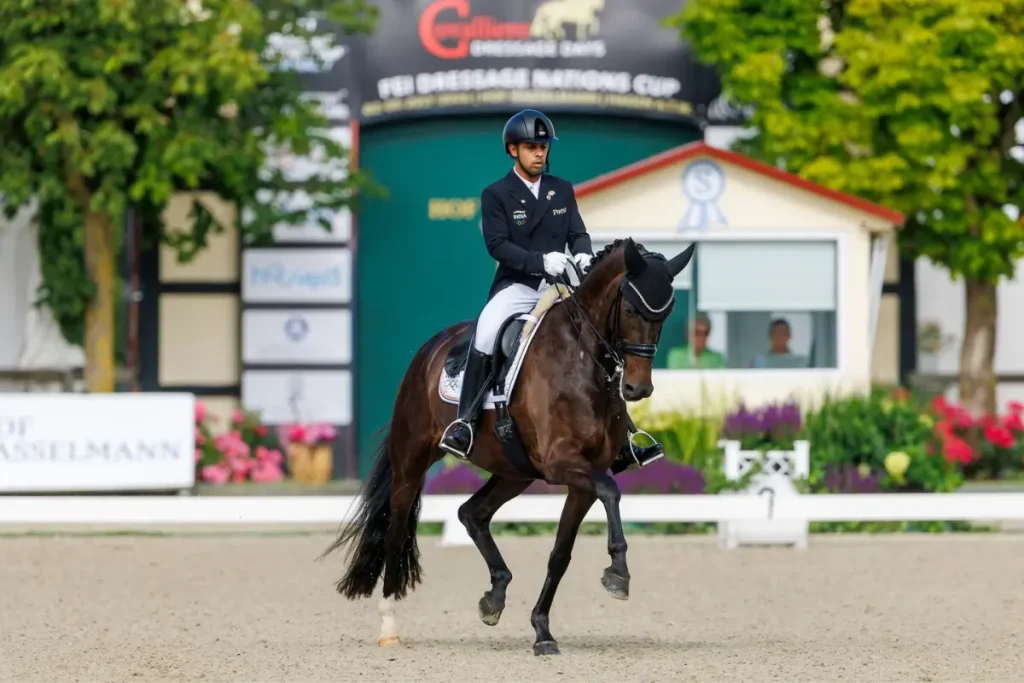 Indischer Dressurreiter Anush Agarwalla auf Straight Horse Floriana beim CDI1* Hagen a.T.W. im Dressurviereck vor Richterhäuschen und Werbewänden.