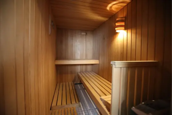 Der Innenraum einer Holzsauna mit stufenförmigen Holzbänken und warmer Wandbeleuchtung.