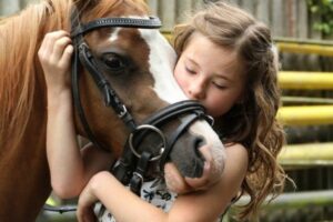 Kinder und Pferde: Junges Mädchen umarmt ihr Pferd