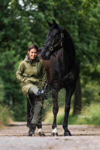 Regenjacke fürs Reiten: Frau mit Pferd in einer Pfütze