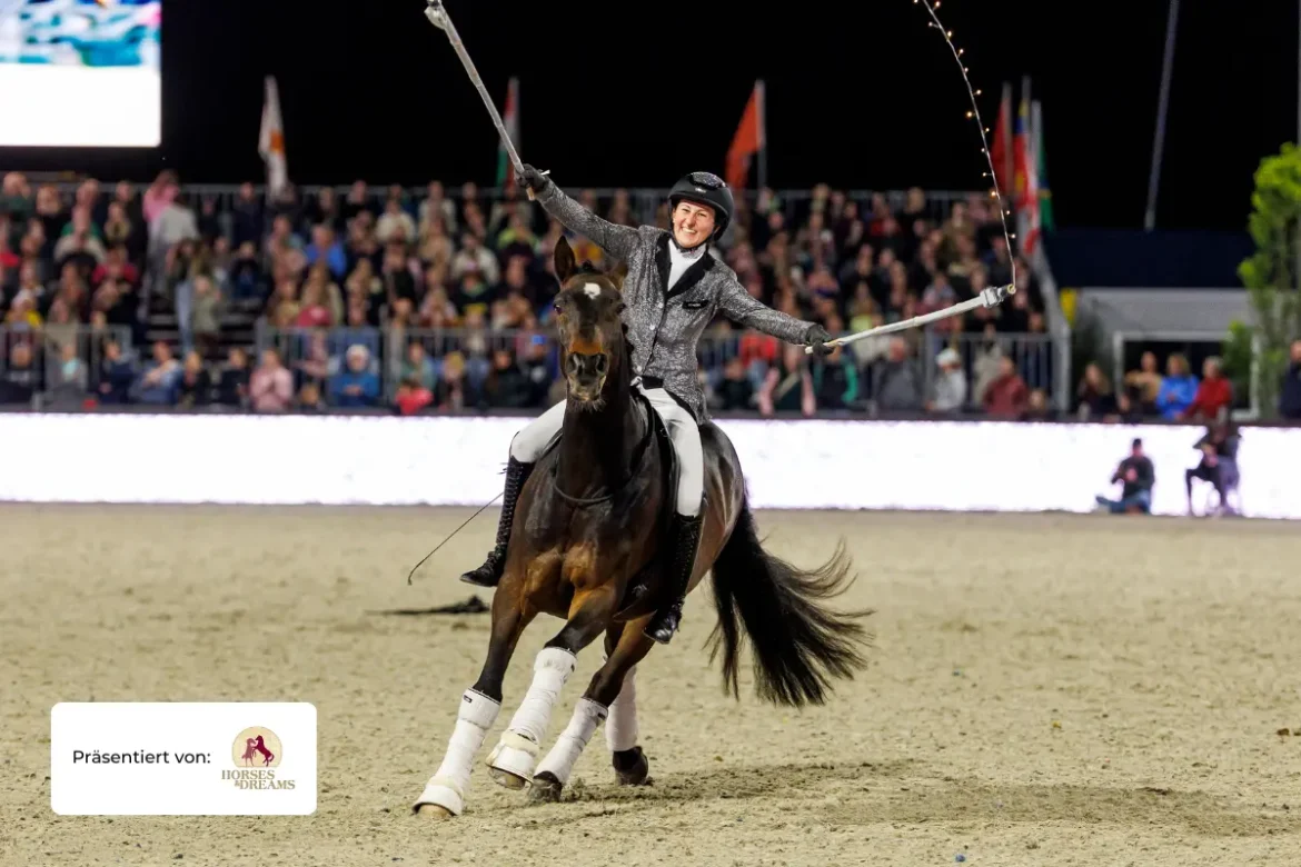 Lisa Röckener reitet auf ihrem Pferd durch eine Arena. Es ist abendliche Stimmung, im Hintergrund erkennt mein Zuschauer auf einer Tribüne.